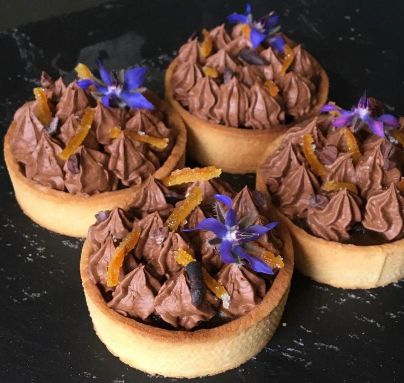 Vegan chocolate orange tart with chocolate orange brownie, orange caramel and chocolate orange aquafaba mousse, decorated with candied orange peel, cocoa nibs and borage flowers